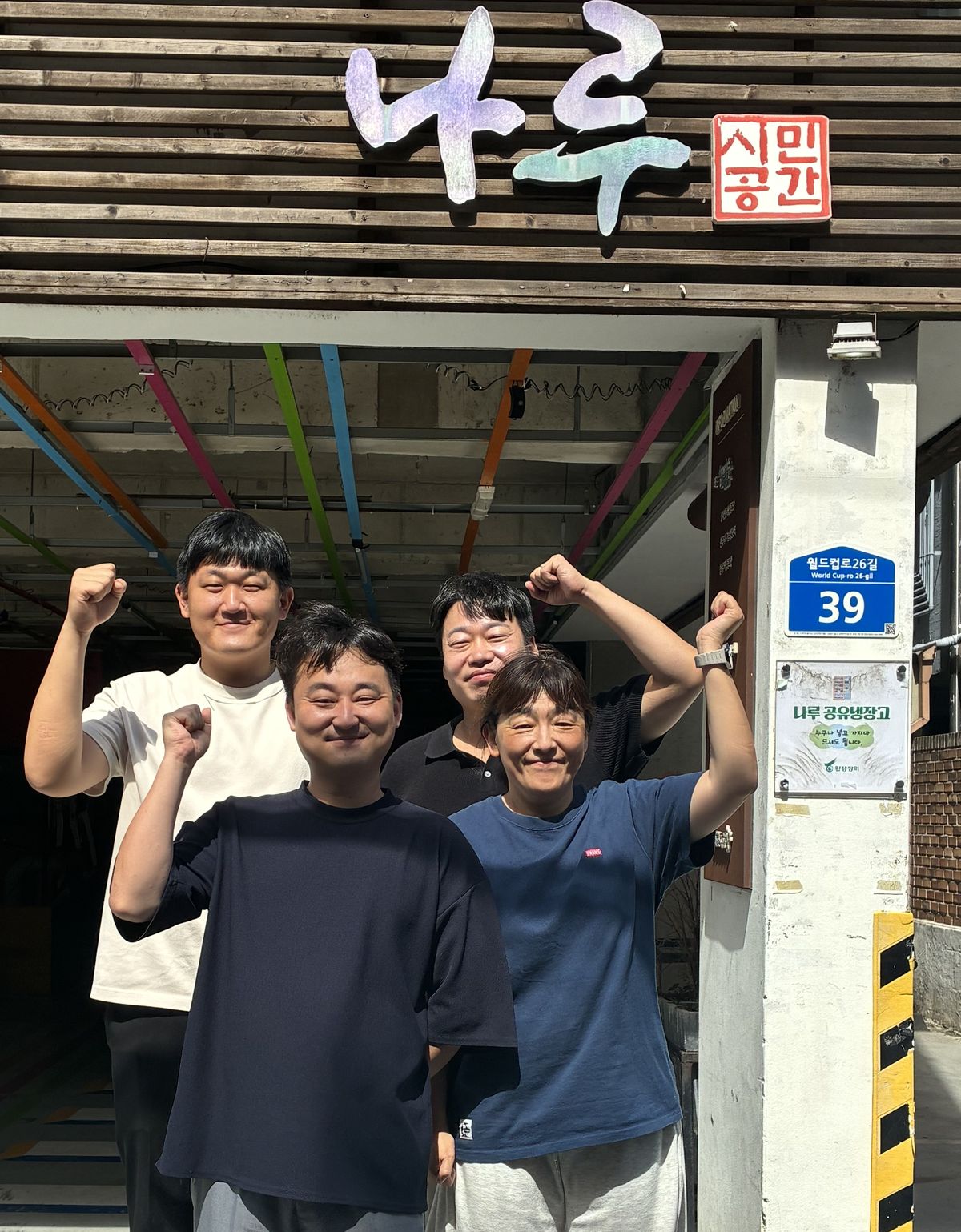 함께하는 시민행동 사무처 활동가 네 명이 건물 앞에서 팔을 들어 보이고 있다